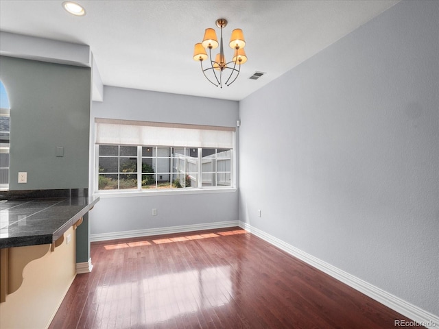 unfurnished dining area featuring an inviting chandelier and hardwood / wood-style floors