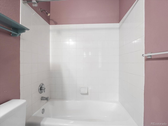 bathroom with tiled shower / bath combo and toilet