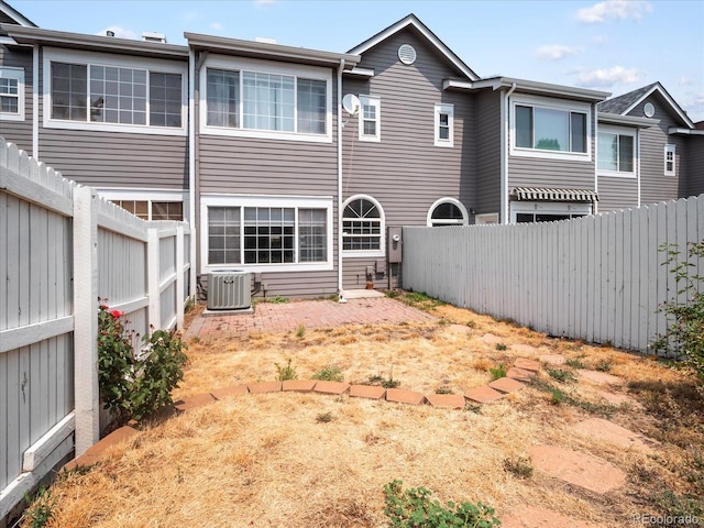 back of property with a fenced backyard and central AC