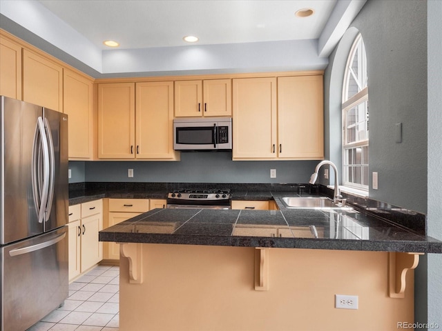 kitchen featuring appliances with stainless steel finishes, sink, kitchen peninsula, and light brown cabinets