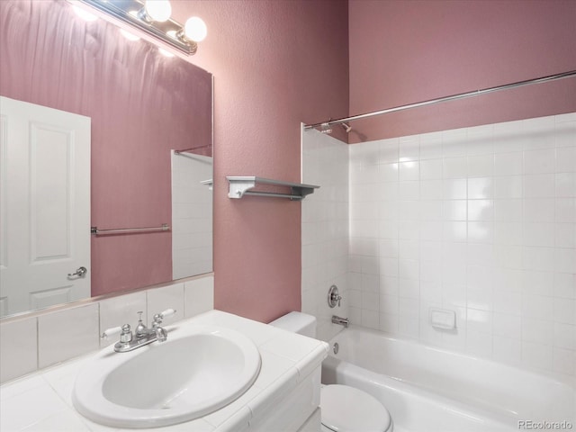 full bathroom featuring toilet, tiled shower / bath, and vanity