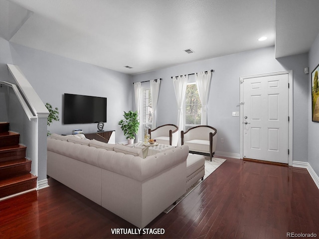 living area featuring baseboards, stairs, visible vents, and wood finished floors