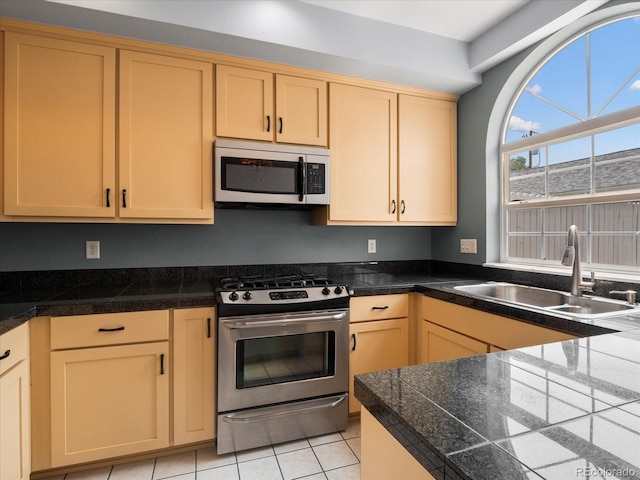 kitchen with light tile patterned flooring, light brown cabinets, a sink, appliances with stainless steel finishes, and tile counters