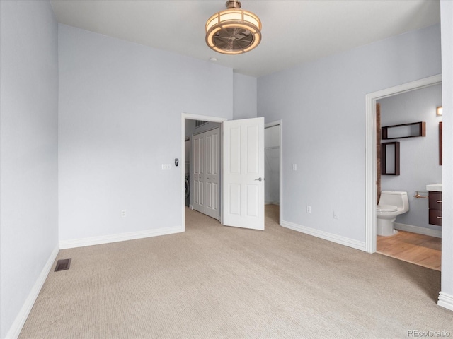 unfurnished bedroom featuring a closet, visible vents, ensuite bathroom, carpet flooring, and baseboards