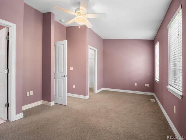 unfurnished bedroom with carpet floors, a walk in closet, ceiling fan, and baseboards