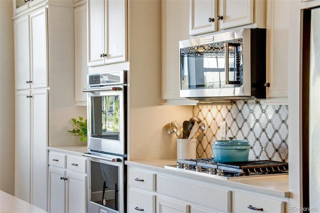 kitchen with light countertops, tasteful backsplash, appliances with stainless steel finishes, and white cabinets