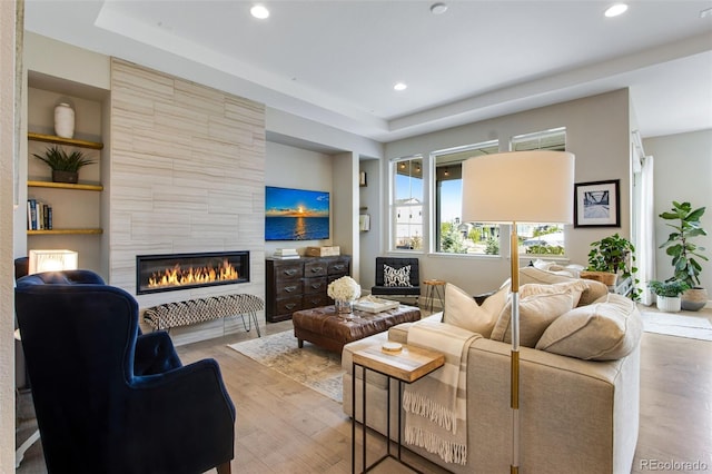 living area featuring a tiled fireplace, wood finished floors, and recessed lighting