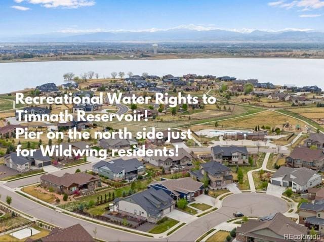 drone / aerial view featuring a water and mountain view and a residential view