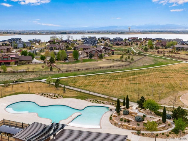 view of pool featuring a water view, a residential view, and fence