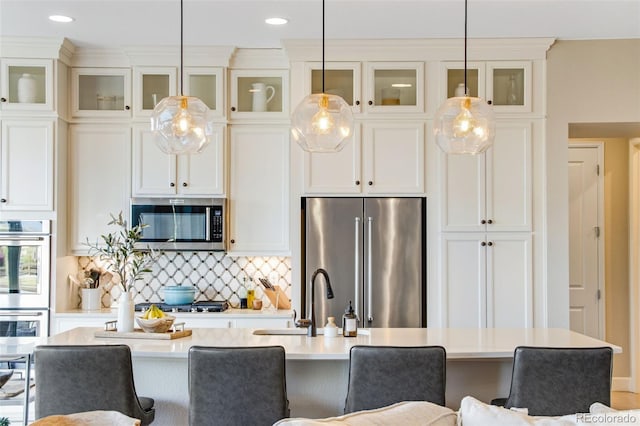 kitchen with stainless steel appliances, an island with sink, a sink, and a kitchen bar