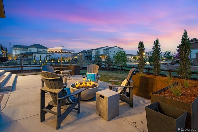 patio terrace at dusk featuring a fire pit and a residential view