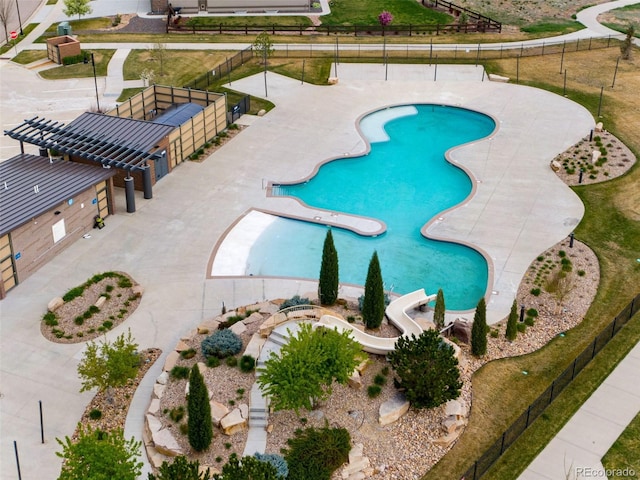 view of swimming pool featuring fence and a water slide