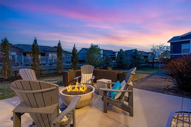 patio terrace at dusk with a residential view, a fire pit, and fence