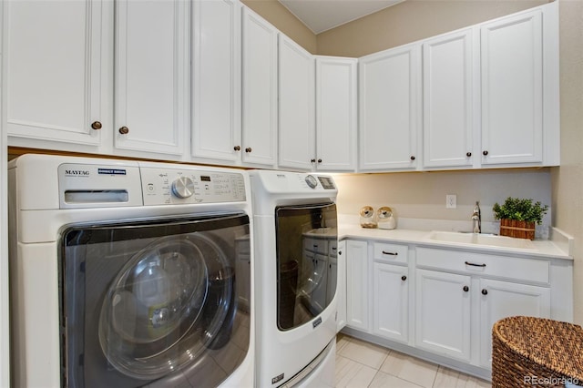 laundry area featuring cabinet space, washer and clothes dryer, light tile patterned floors, and a sink