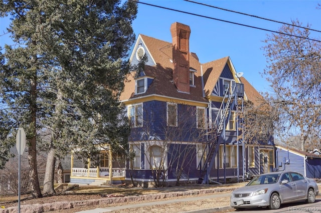 victorian home featuring roof with shingles and a chimney