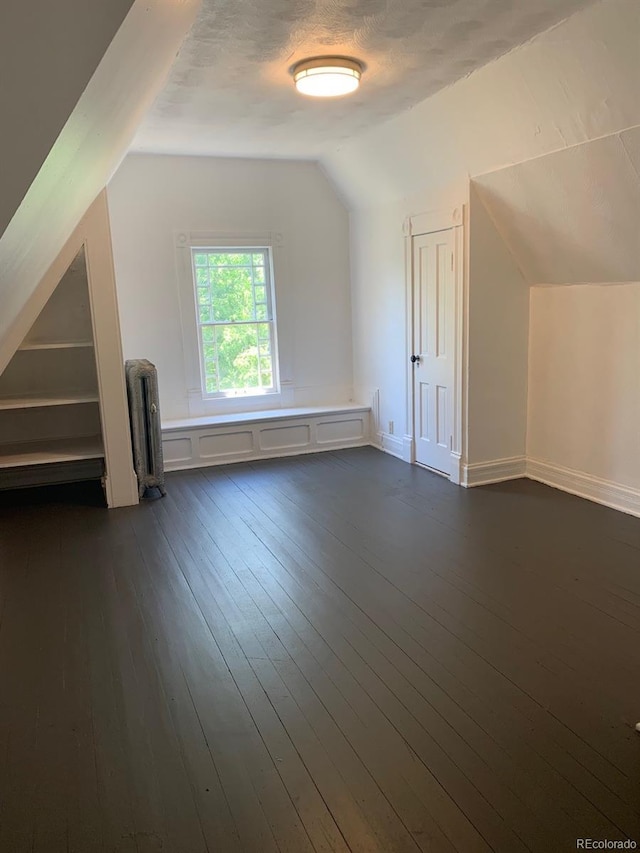 bonus room featuring dark wood-style flooring, vaulted ceiling, a textured ceiling, and radiator heating unit