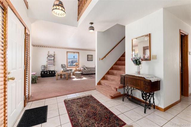 entrance foyer with light carpet, light tile patterned flooring, stairs, and baseboards