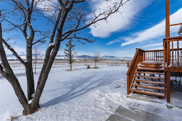 yard layered in snow featuring stairs and a deck with mountain view