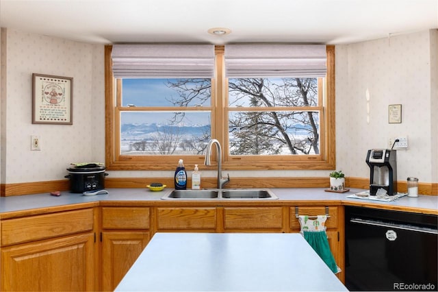kitchen featuring a sink, light countertops, dishwasher, brown cabinetry, and wallpapered walls