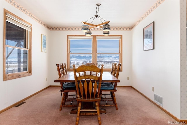 dining space featuring baseboards, visible vents, and light colored carpet