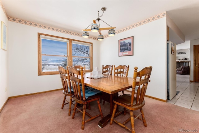 dining space featuring baseboards, light tile patterned floors, and light colored carpet