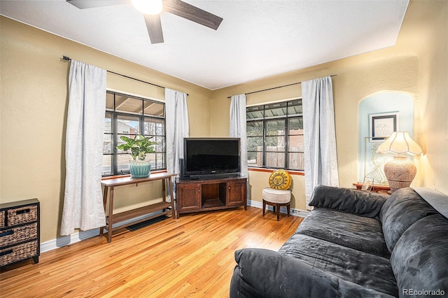 living room featuring light wood-style floors, a healthy amount of sunlight, ceiling fan, and baseboards