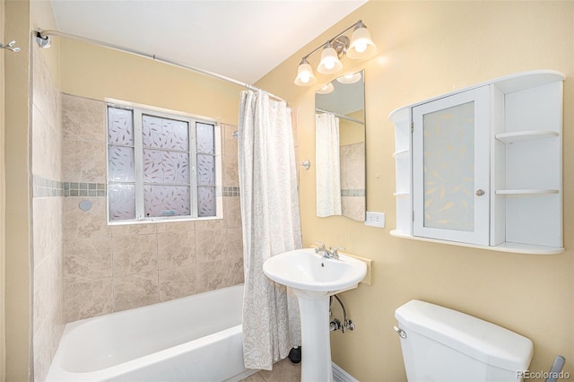 bathroom featuring toilet, a sink, and shower / bath combination with curtain