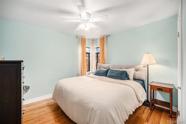 bedroom with a ceiling fan, baseboards, and wood finished floors