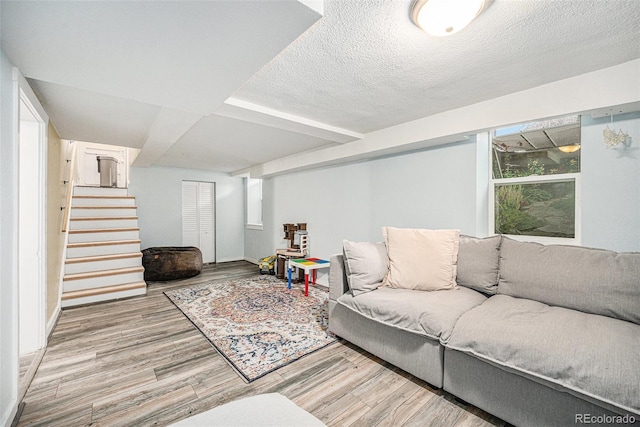 living room featuring stairs, a textured ceiling, and wood finished floors