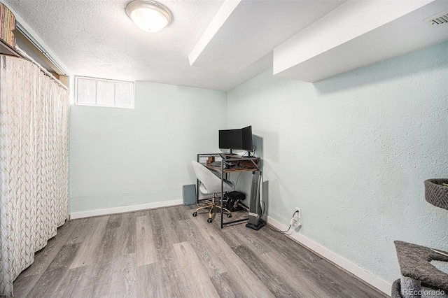 office area featuring baseboards, a textured ceiling, visible vents, and wood finished floors