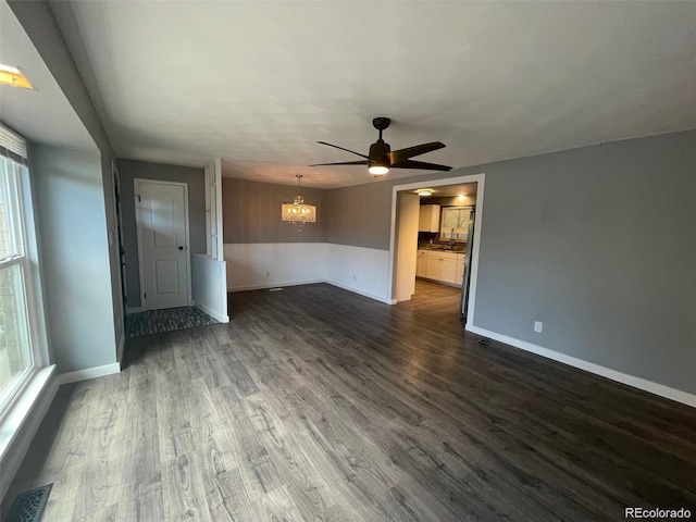 empty room featuring baseboards, dark wood finished floors, visible vents, a sink, and ceiling fan with notable chandelier