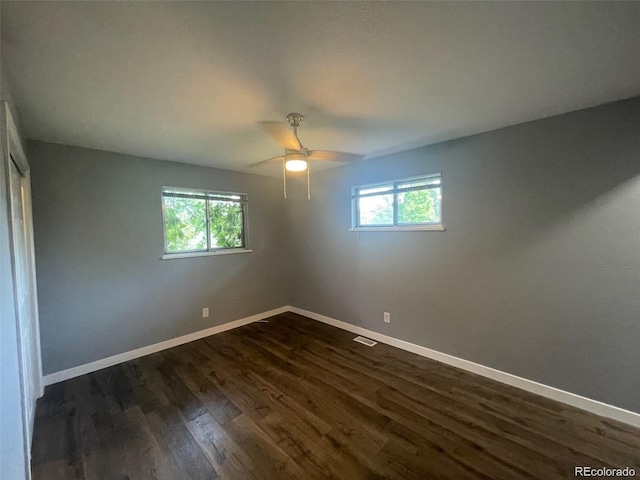 spare room featuring dark wood-style flooring, baseboards, a ceiling fan, and visible vents