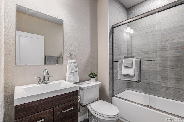 full bathroom featuring vanity, combined bath / shower with glass door, and toilet