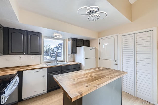 kitchen with butcher block counters, sink, white appliances, and light hardwood / wood-style flooring