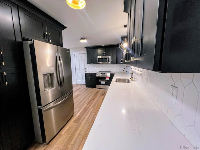 kitchen with pendant lighting, appliances with stainless steel finishes, sink, and tasteful backsplash