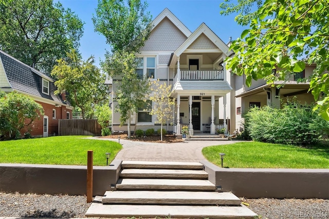 rear view of property with fence, a lawn, and a balcony
