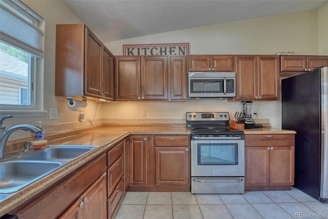 972 Columbine Ave, Colorado Springs, CO 80904 - kitchen featuring stainless steel appliances, lofted ceiling, light tile patterned floors, light countertops, and brown cabinets