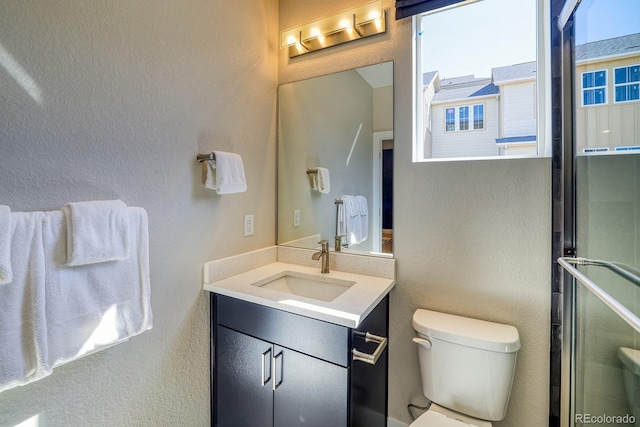 bathroom featuring a shower stall, toilet, vanity, and a textured wall