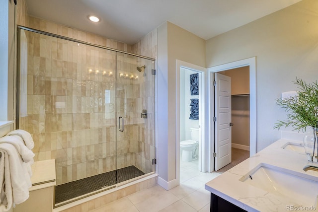 bathroom with tile patterned floors, a shower stall, toilet, double vanity, and recessed lighting