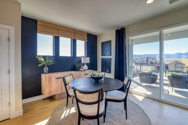 dining room featuring light wood finished floors, a mountain view, baseboards, and recessed lighting