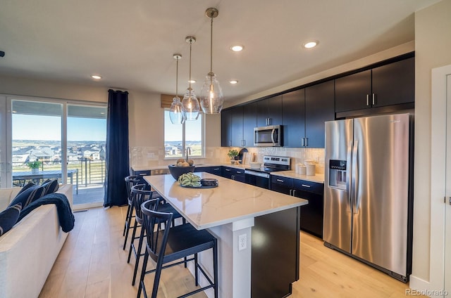 kitchen with appliances with stainless steel finishes, a breakfast bar, recessed lighting, a kitchen island, and dark cabinets