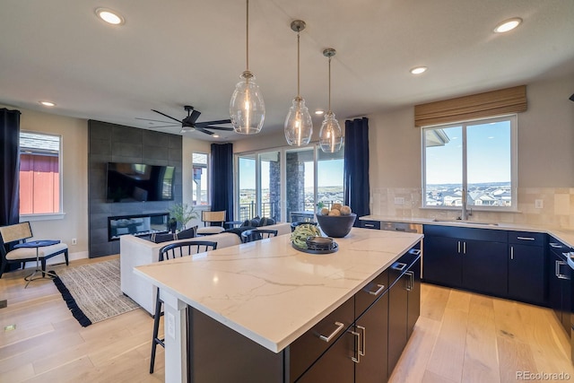 kitchen featuring a sink, a kitchen island, recessed lighting, light wood-type flooring, and open floor plan