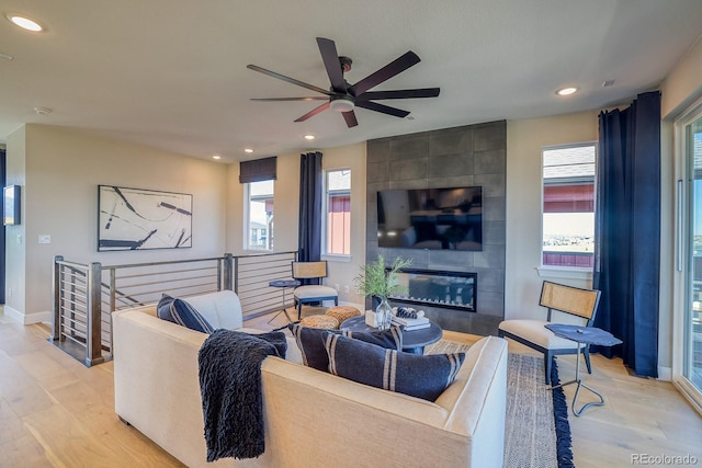 living room featuring light wood-style flooring, baseboards, ceiling fan, healthy amount of natural light, and recessed lighting
