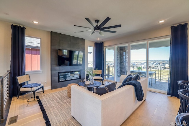 living area featuring light wood finished floors, ceiling fan, healthy amount of natural light, a fireplace, and recessed lighting
