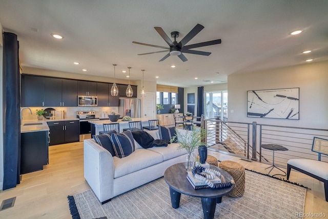living area featuring recessed lighting, light wood-type flooring, and a ceiling fan