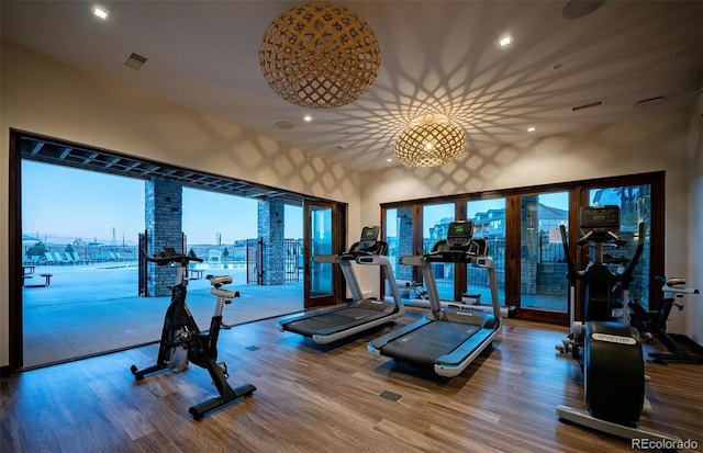 exercise room with wood finished floors, recessed lighting, and a high ceiling
