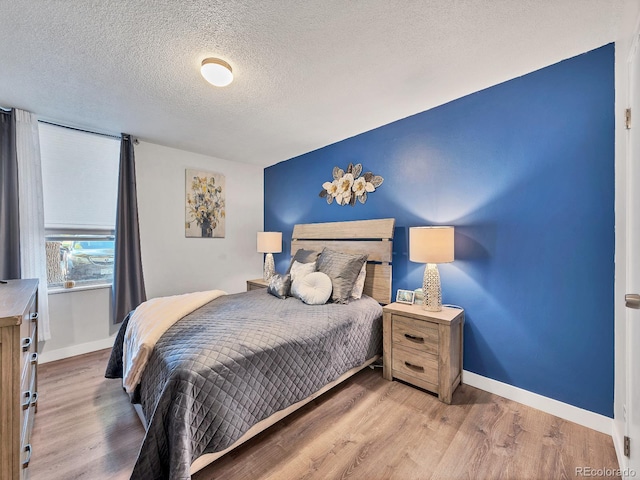 bedroom with light wood-type flooring and a textured ceiling