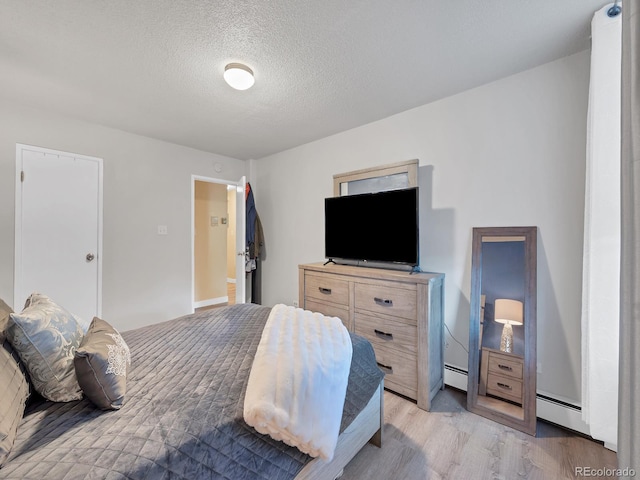 bedroom featuring a baseboard radiator, light wood-type flooring, and a textured ceiling