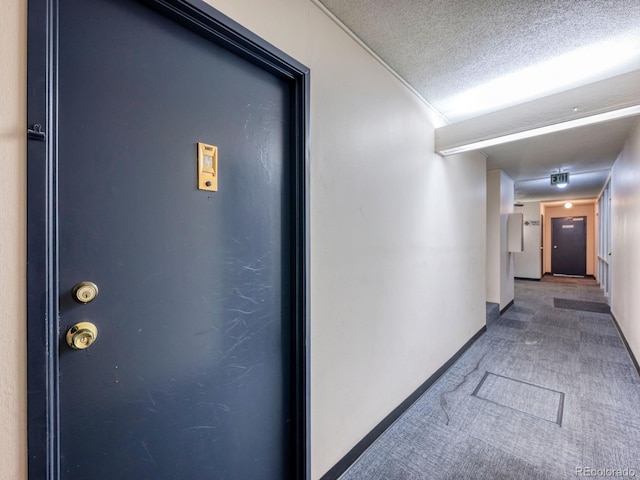 hall with carpet floors and a textured ceiling