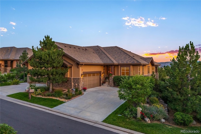 view of front of house with an attached garage, a tile roof, stone siding, stucco siding, and driveway